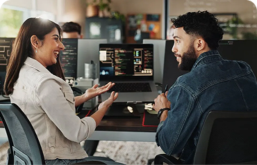 Two colleagues having a discussion in front of a computer monitor.